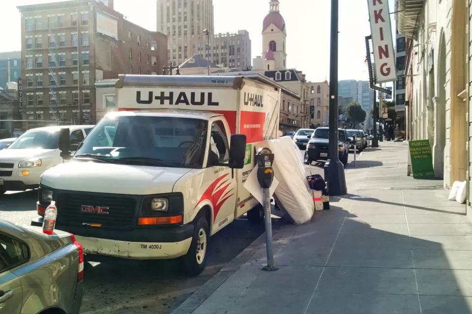 U-Haul moving van parked by a curb in San Francisco with mattress leaning against it